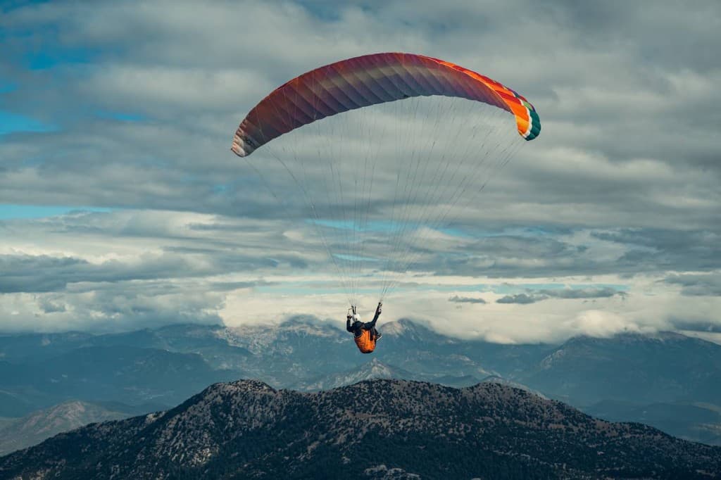 Paraglider with a red wing above mountain ridges