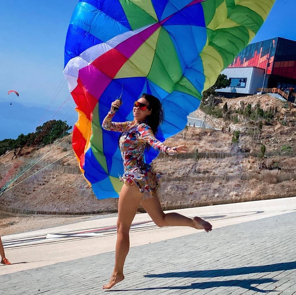 Joyful pilot dancing with a colourful canopy on launch